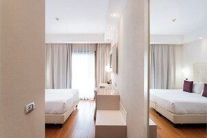 Habitación de hotel con dos camas, un escritorio, una silla y un espejo.