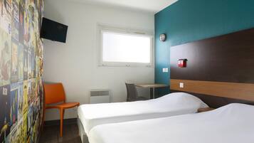 Una camera d'albergo con due letti, una scrivania, una sedia, una TV fissata al muro e una finestra.
