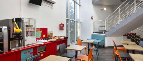 Una cafetería moderna con techos altos, una escalera y diversas opciones de asientos.
