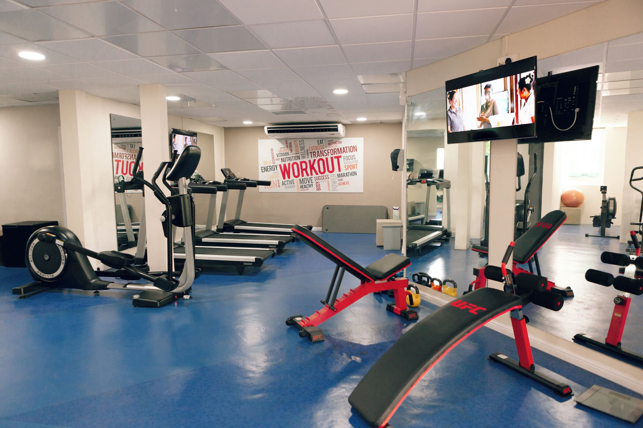 Une salle de sport équipée de tapis de course, d’un vélo d’appartement et d’une zone dédiée aux exercices de développé couché.