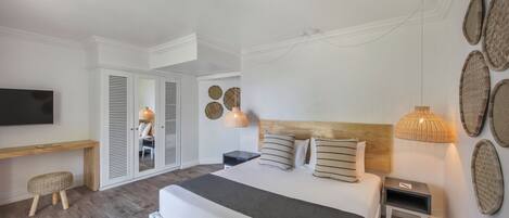 A modern bedroom with a large bed, bedside tables, a TV, and a wardrobe.