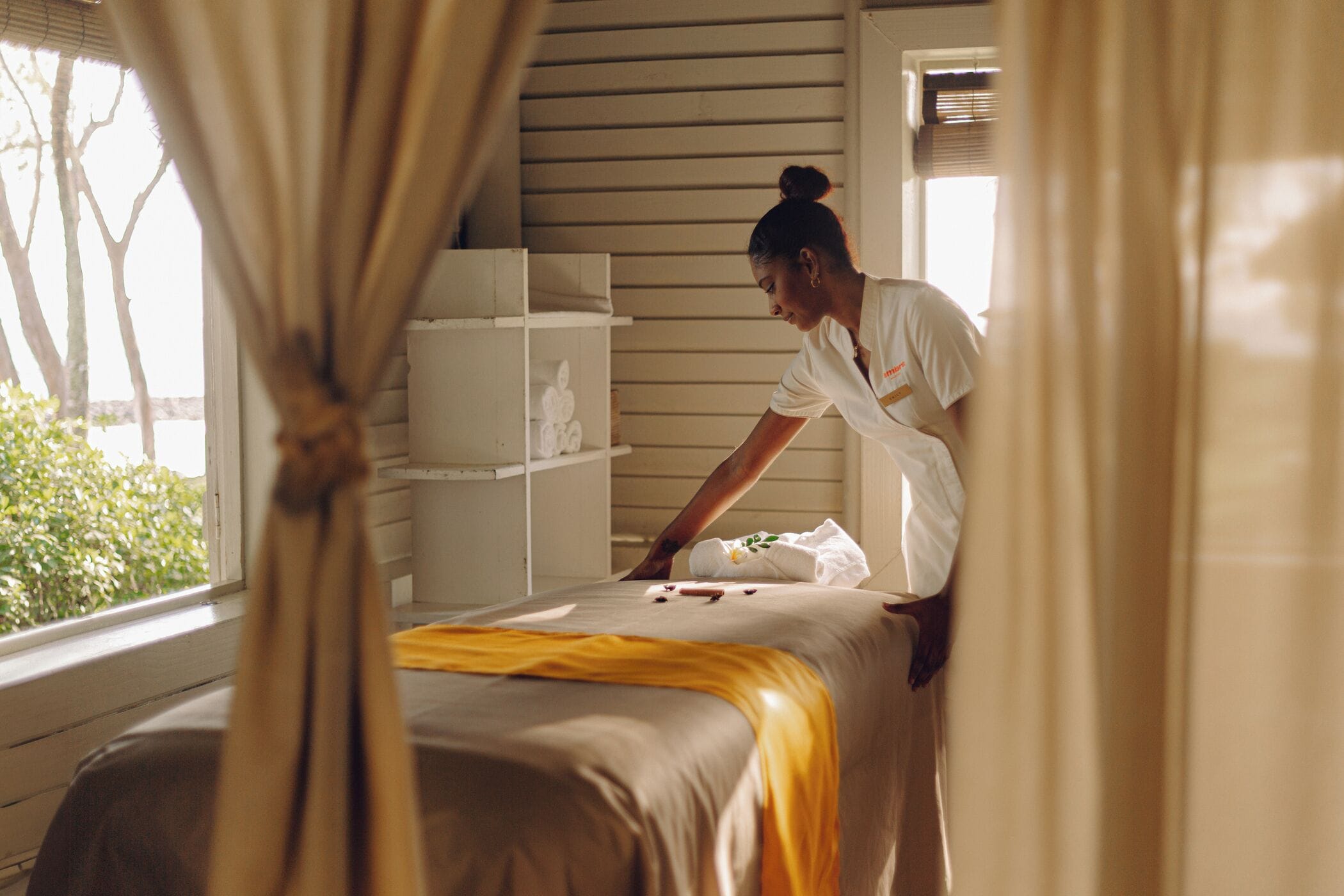 A room with a bed, a window with curtains, and a shelf with decorative items.