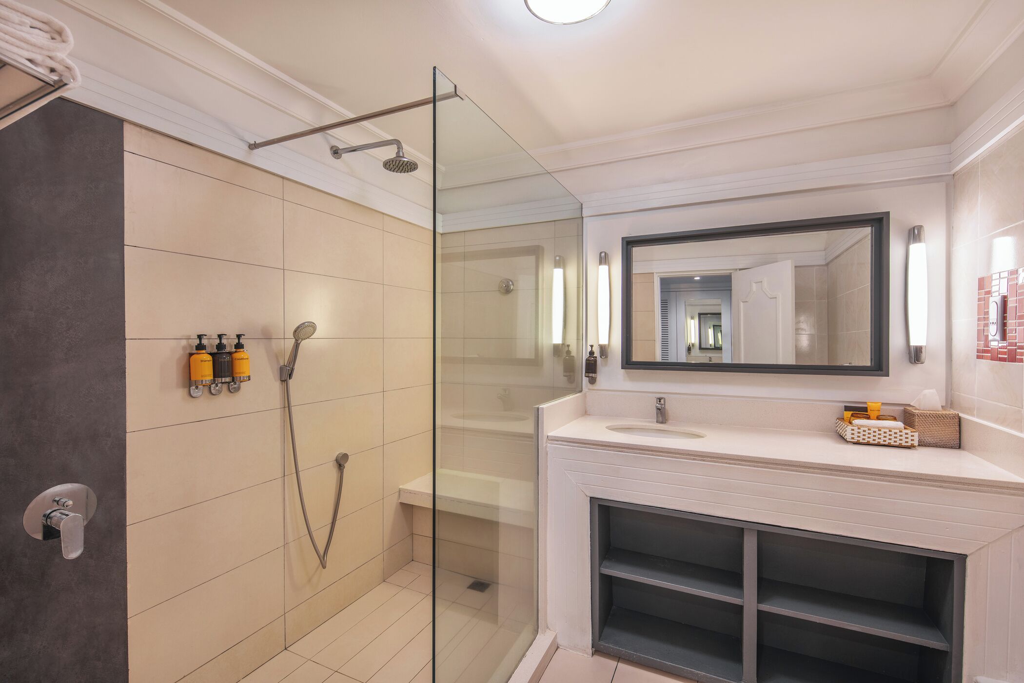 Une salle de bain moderne dotée d’une douche à parois de verre, d’un meuble-lavabo blanc avec un miroir et d’une étagère intégrée.
