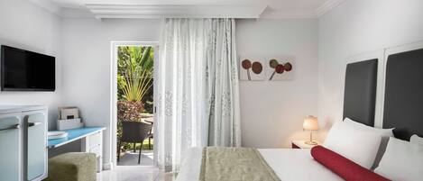 Ein Hotelzimmer mit einem Bett, einem Schreibtisch, einem Fernseher und Blick ins Freie.