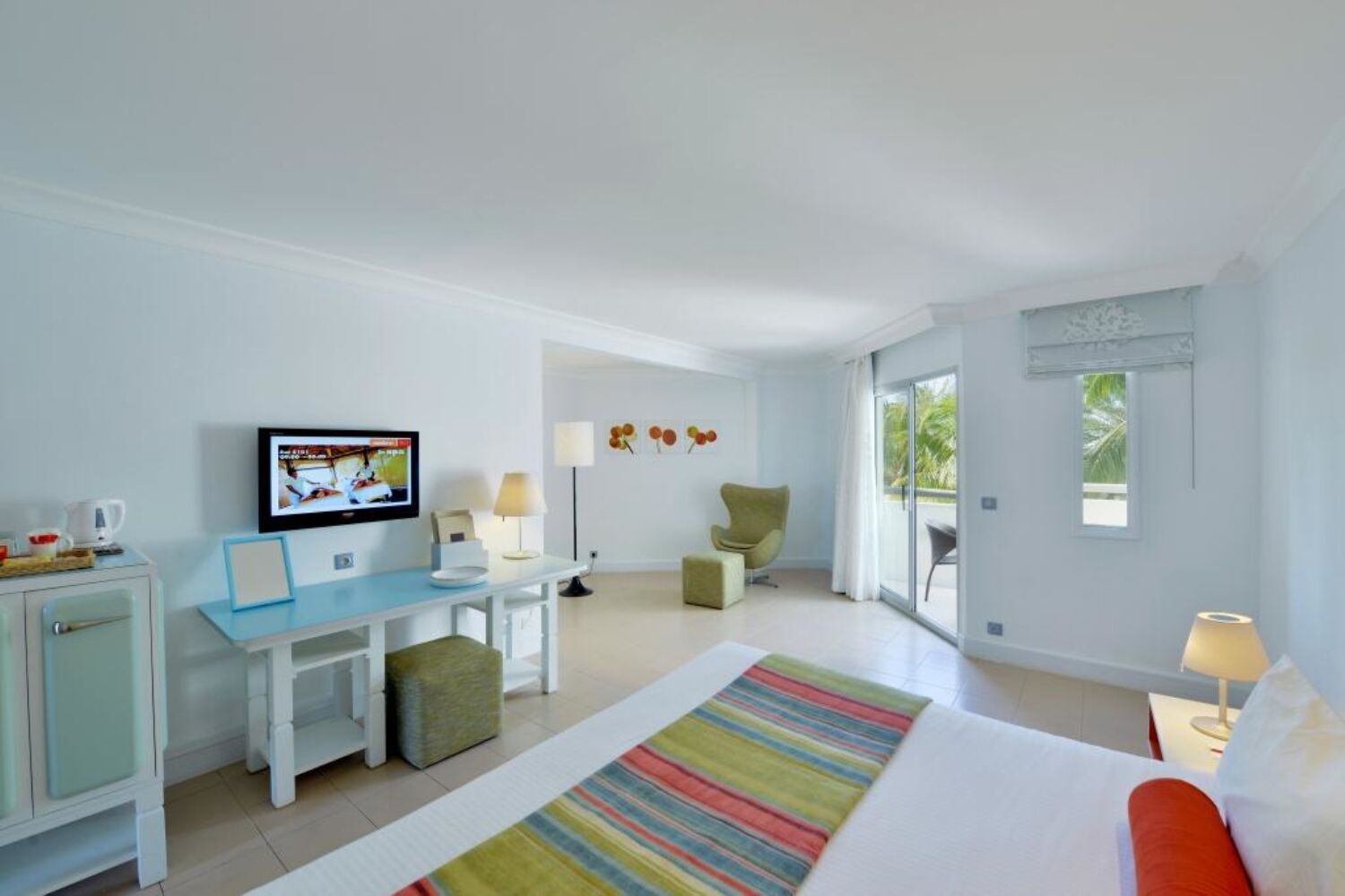 A hotel room with a bed, a desk, a television, and a view of the outdoors.
