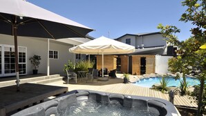 A backyard with a hot tub, wooden deck, outdoor seating, and a swimming pool. - Wai Ora Lakeside Spa Resort (Rotorua)