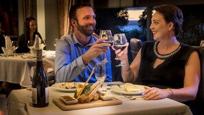 A couple seated at a table with wine glasses, a bottle of wine, and a meal. - Wai Ora Lakeside Spa Resort (Rotorua)