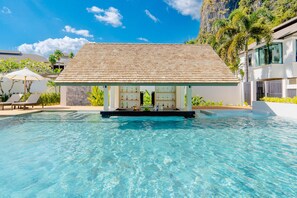 A clear swimming pool with lounge chairs and a bar area with bottles. - Bhu Nga Thani Resort & Villas Railay (Krabi)