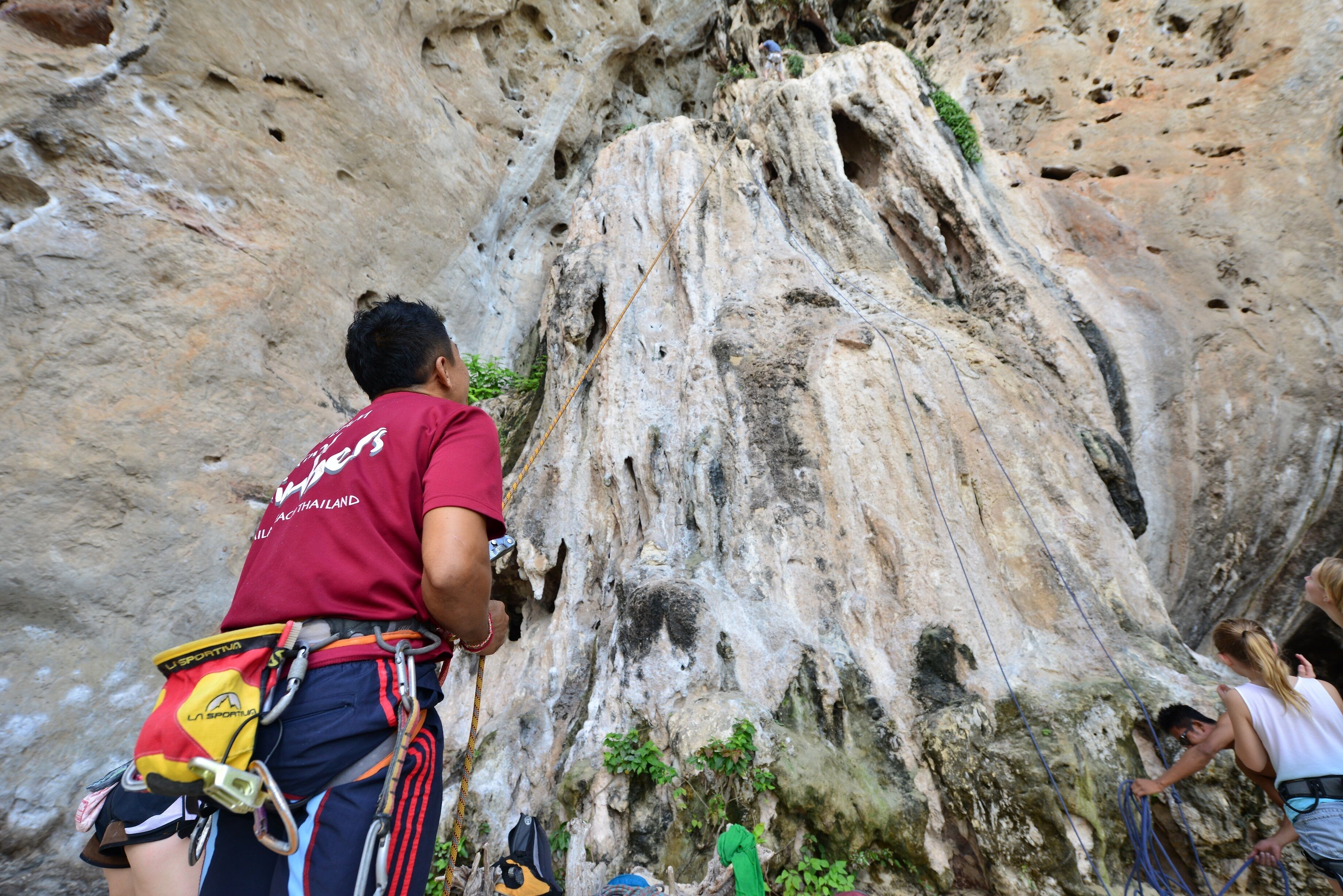 A person climbing a rocky cliff with climbing gear.