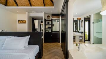 Una habitación de hotel moderna con una cama grande, baño separado con lavamanos y espejo amplios, y piso de madera con patrón de espiga.