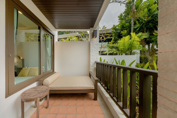 A balcony with a cushioned bench, a small wooden table, and a railing. - Bhu Nga Thani Resort & Villas Railay (Krabi)