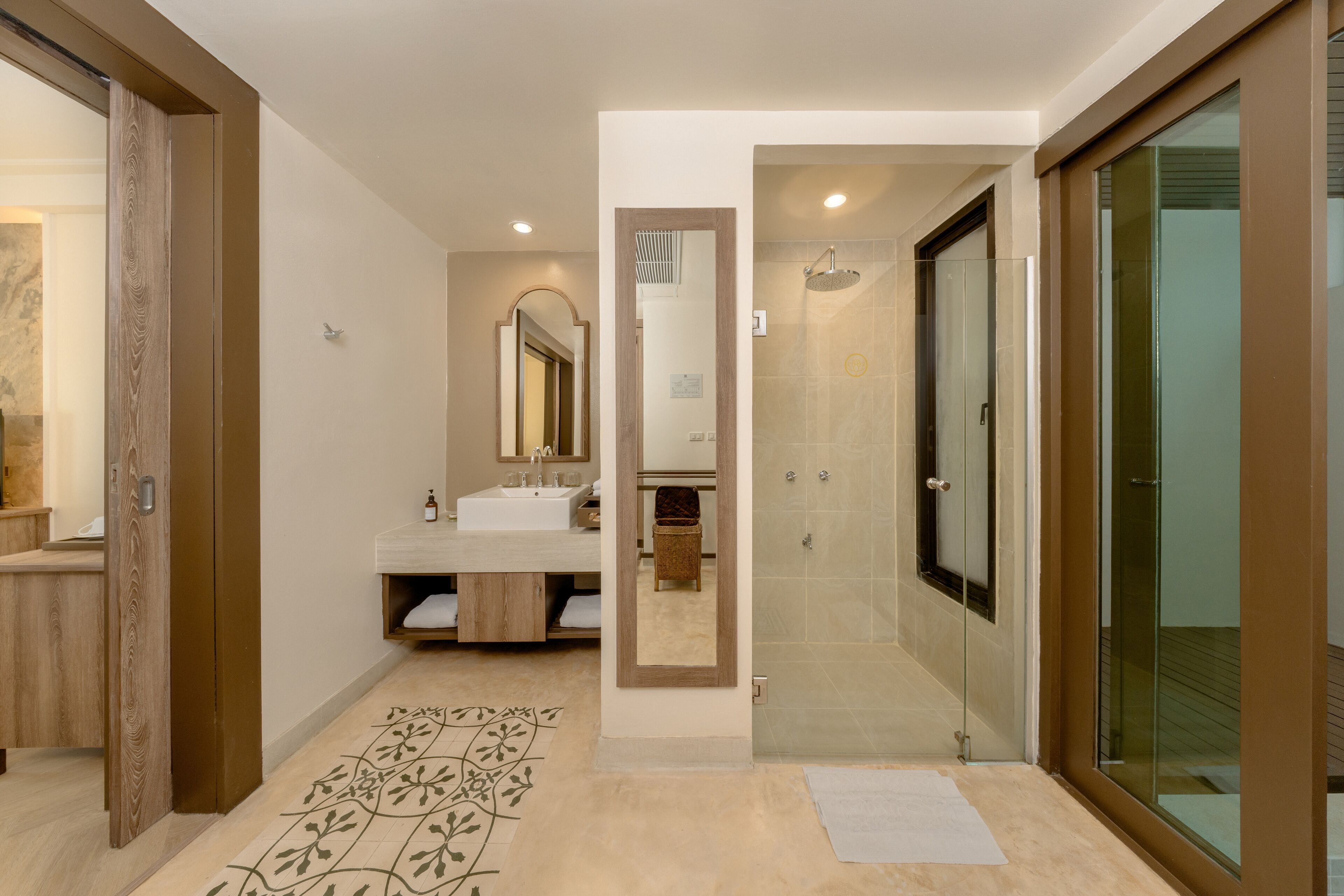 A modern bathroom with a large mirror, a sink, and a shower area.