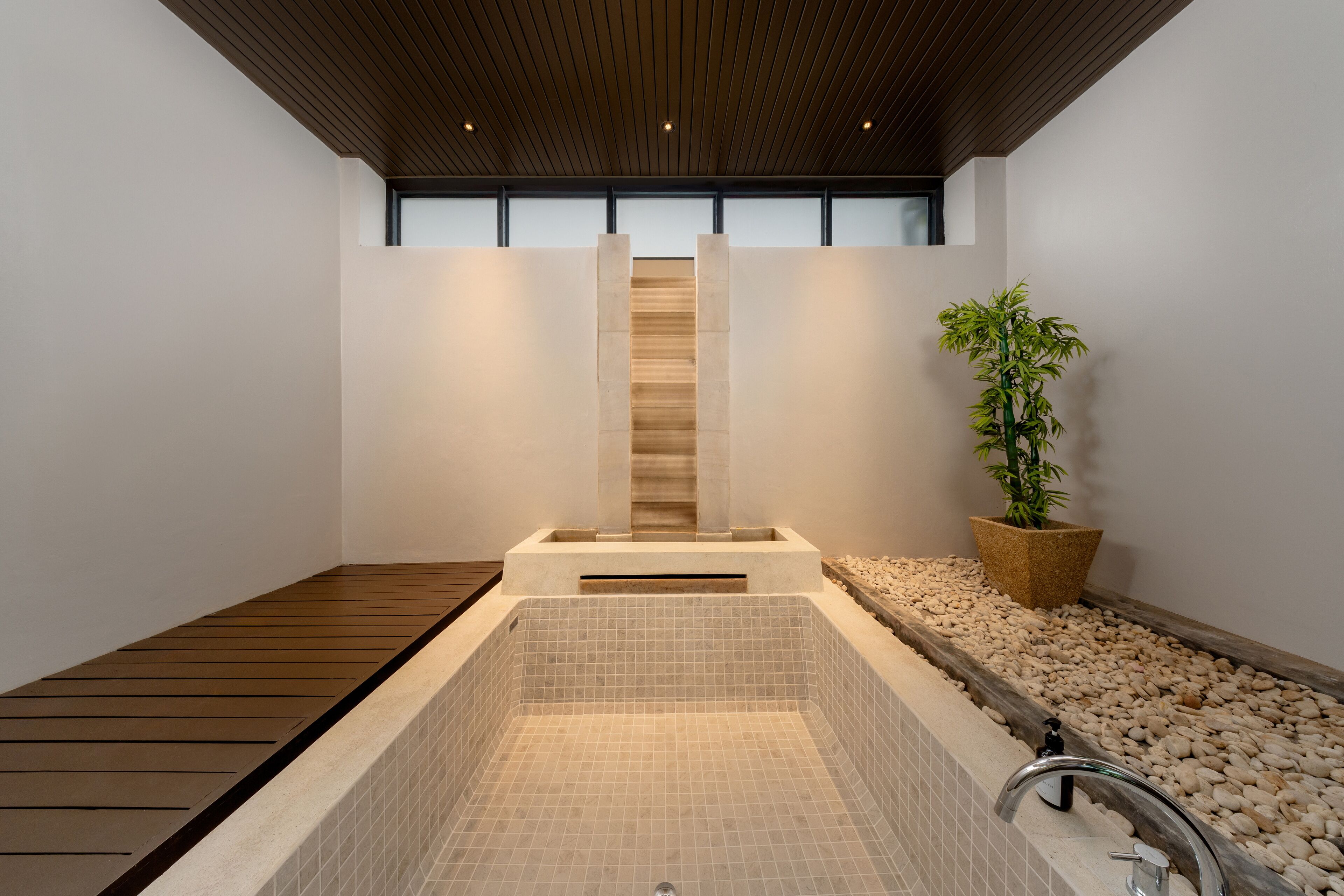 A spa area with a wooden deck, a tiled hot tub, and a potted plant.