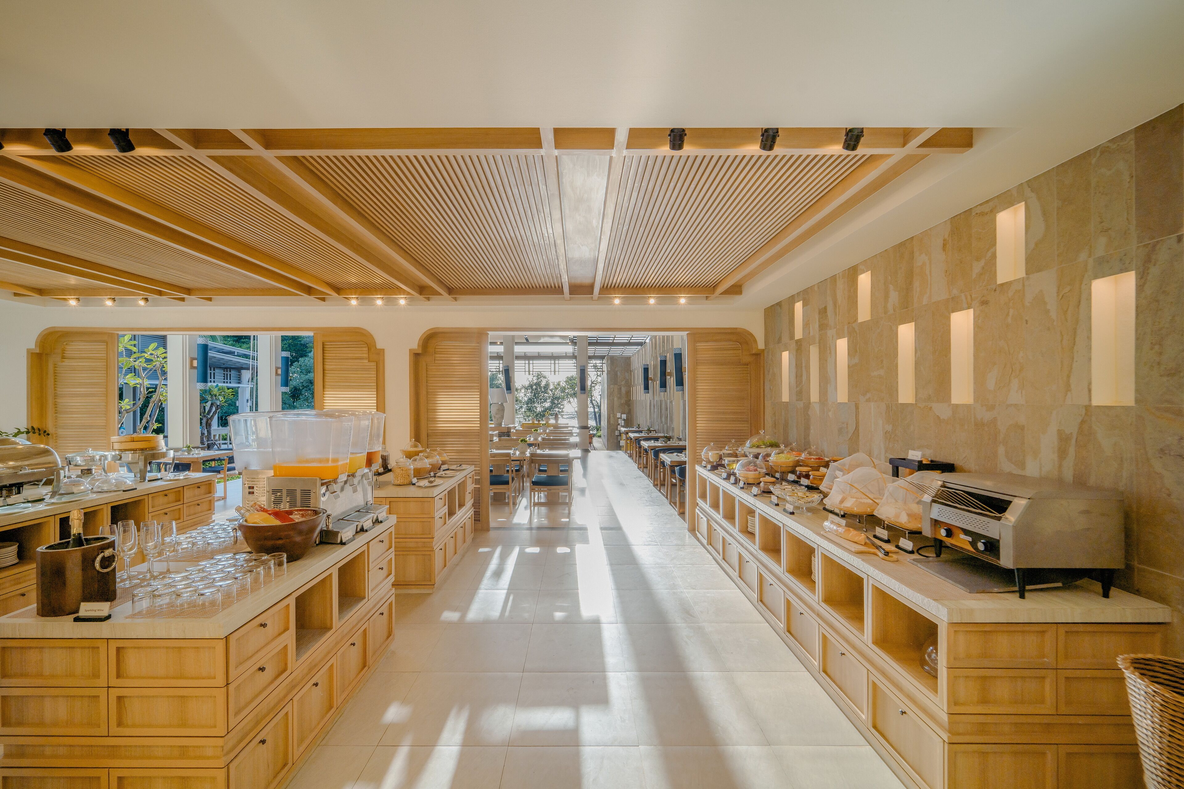 A spacious kitchen with wooden cabinets, a large island with kitchen appliances, and a view through the open archway.