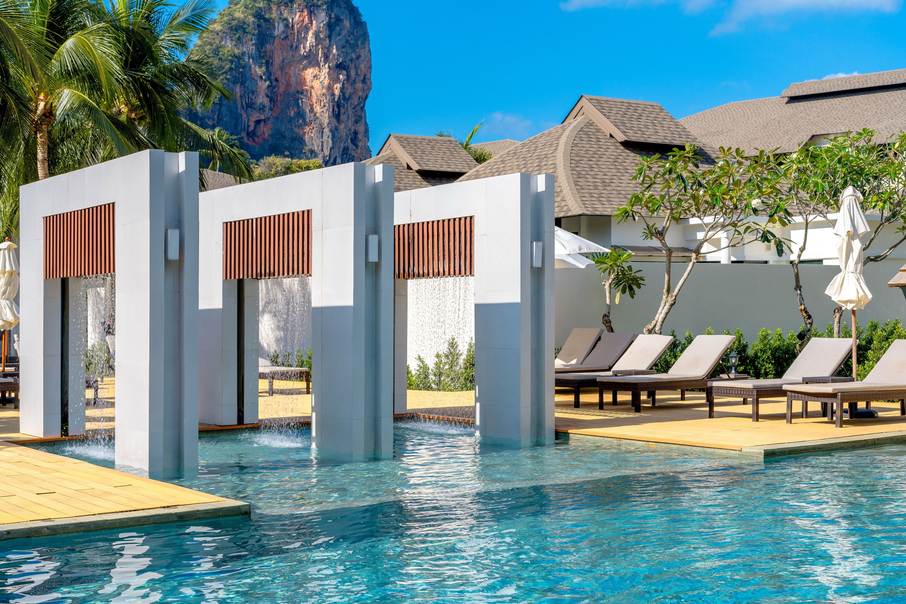 A swimming pool with lounge chairs and a waterfall feature.