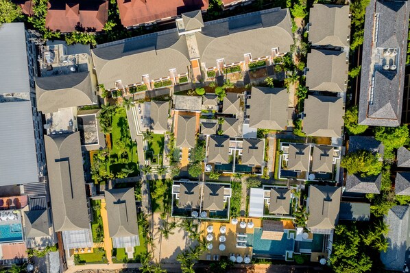 Vista aérea de un complejo turístico con varias edificaciones, piscinas al aire libre y exuberante vegetación.