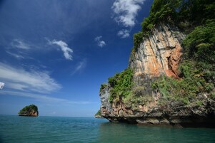 A coastal landscape with a prominent cliff and a small island in the water.