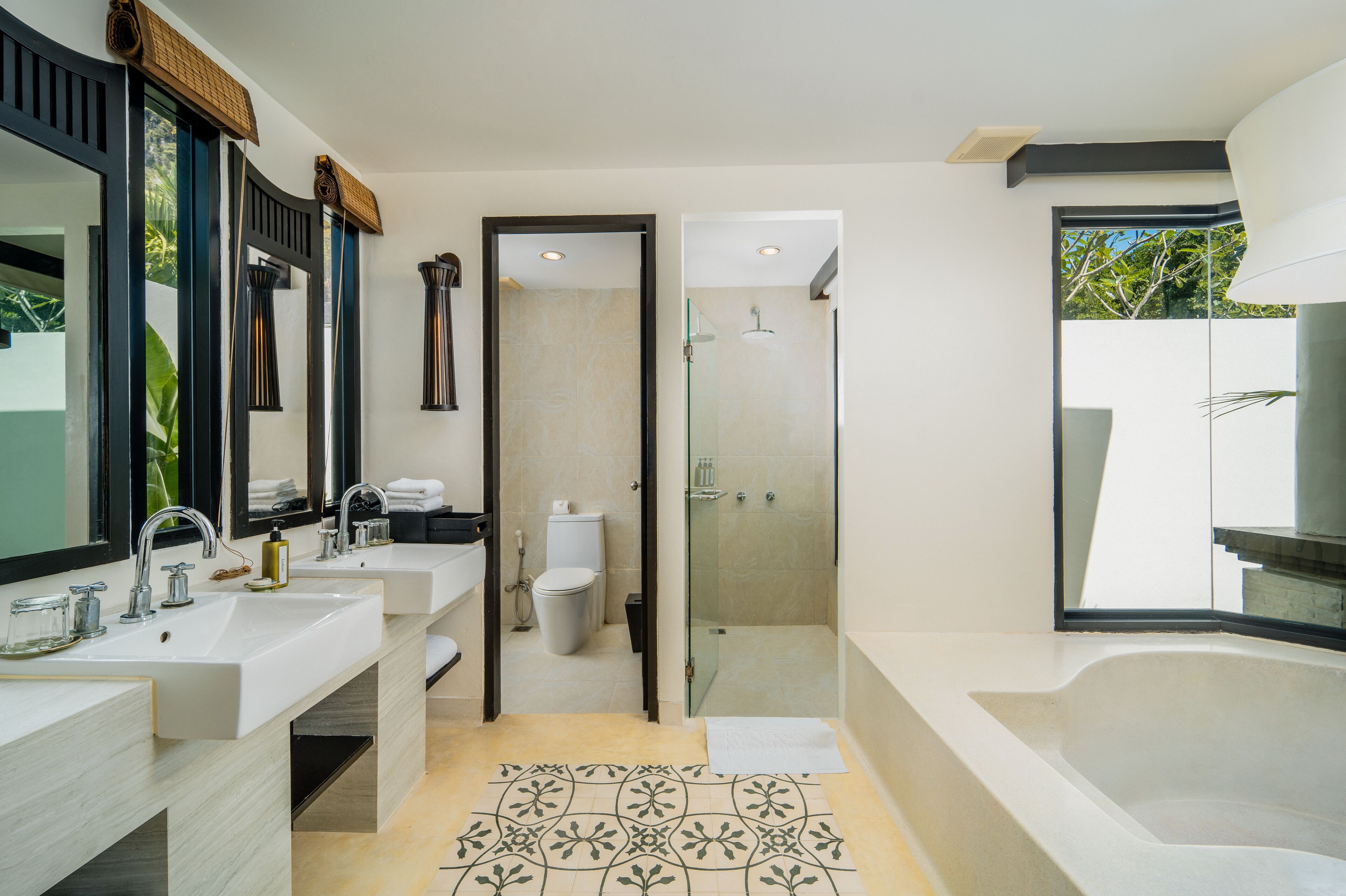Un baño moderno con dos lavamanos, cabina de ducha con paredes de vidrio y una bañera grande.