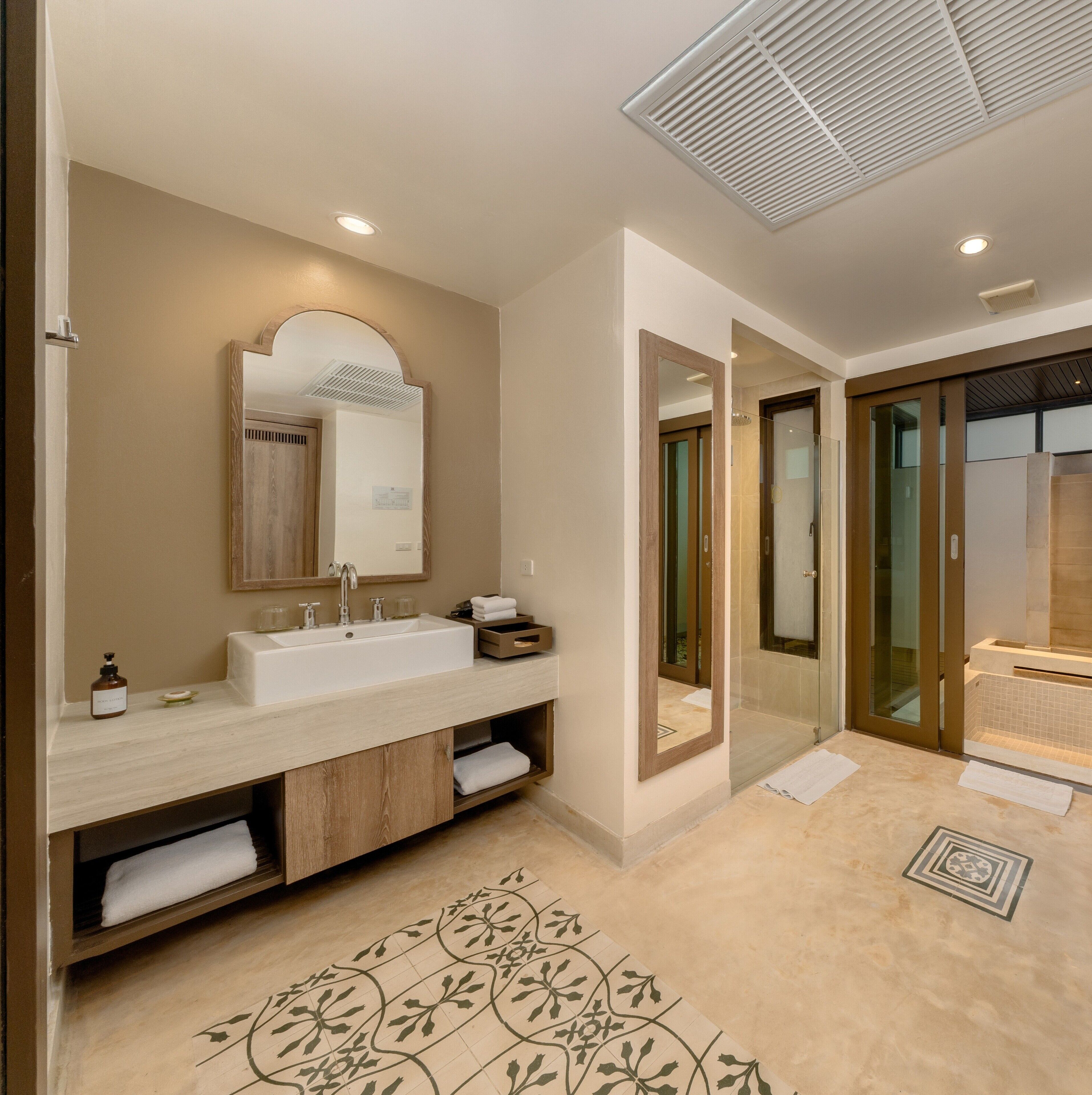 A modern bathroom with a double sink, a large mirror, and a shower area.