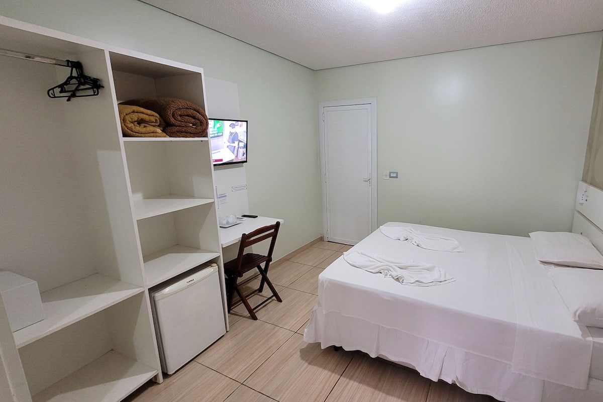 Une chambre à coucher comprenant un lit, un bureau, une chaise, une armoire et un téléviseur.
