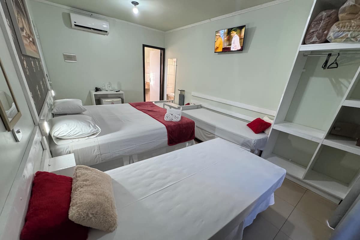 Une chambre d’hôtel avec deux lits, une télévision, une armoire et un bureau avec une chaise.