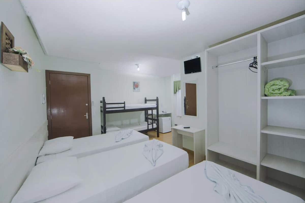 Une chambre avec des lits superposés, un bureau, une chaise, une armoire et un téléviseur.
