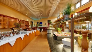 A buffet area with a variety of food stations, wooden paneling, and potted plants. - Hotel Bayern Vital (Bad Reichenhall)
