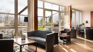 A modern interior with large windows, a sofa, chairs, and a small table.