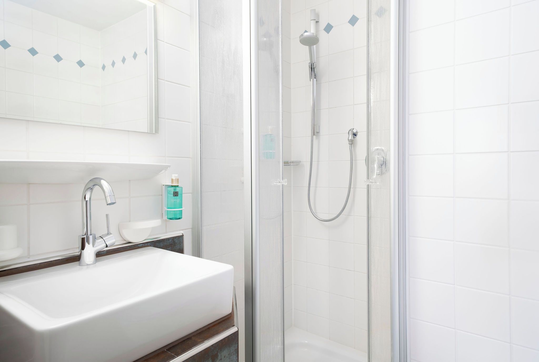 A bathroom with a white sink, a mirror, and a glass-enclosed shower.