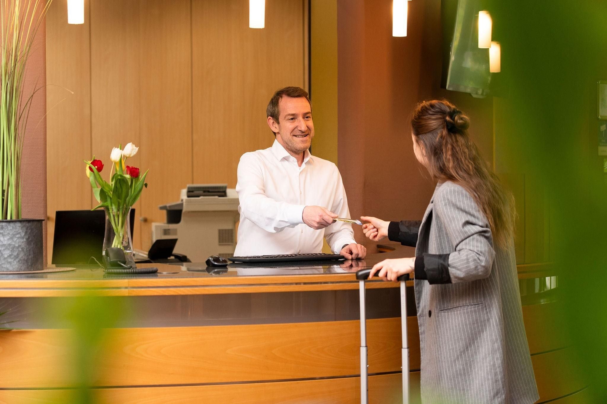 Een receptiebalie waar een man een creditcard aan een vrouw overhandigt.