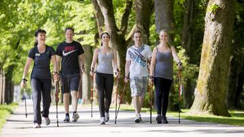 A group of people walking on a paved path in a park with trees on both sides.