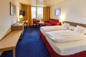 Una habitación de hotel con cama, escritorio, silla, sofá y televisor.