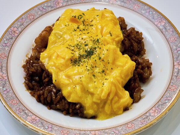 Une assiette de nourriture nappée d’une sauce crémeuse et garnie d’herbes, le tout présenté dans une assiette à motifs floraux.