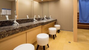 A modern bathroom with a marble countertop, multiple sinks, and white stools. - APA Hotel Okayama Ekimae (Okayama)