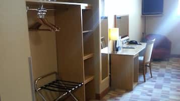 A hotel room with a bed, a desk, a chair, a TV, and a wardrobe.