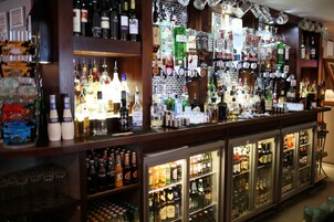 Zona de bar con estantes llenos de botellas de licores y vasos.