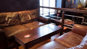 A brown leather sofa and a wooden coffee table in a room with wooden flooring and a window with blinds. - Greyfriars Inn by Greene King Inns (St. Andrews)