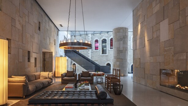 A spacious lobby with a modern fireplace, leather sofas, and a staircase leading to upper floors.