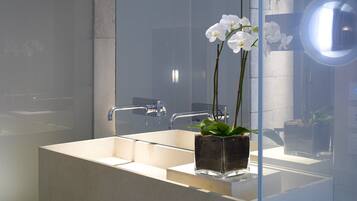 A modern bathroom with a large mirror, a rectangular sink, and a potted orchid.