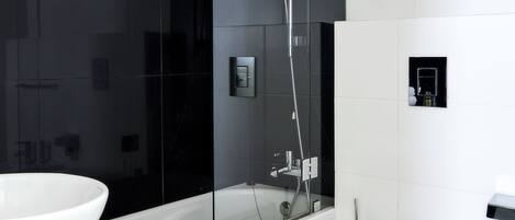 A modern bathroom with a glass-enclosed shower, a white toilet, and a large white sink.