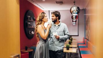 Um interior moderno com uma parede de destaque vermelha, um lustre pendurado e um espaço de estar com bancos.