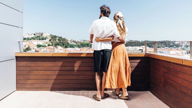 Una pareja parada en un balcón con vista a la ciudad.