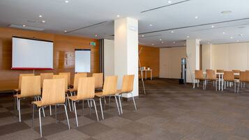 A conference room with wooden chairs and tables, a whiteboard, and a projection screen.