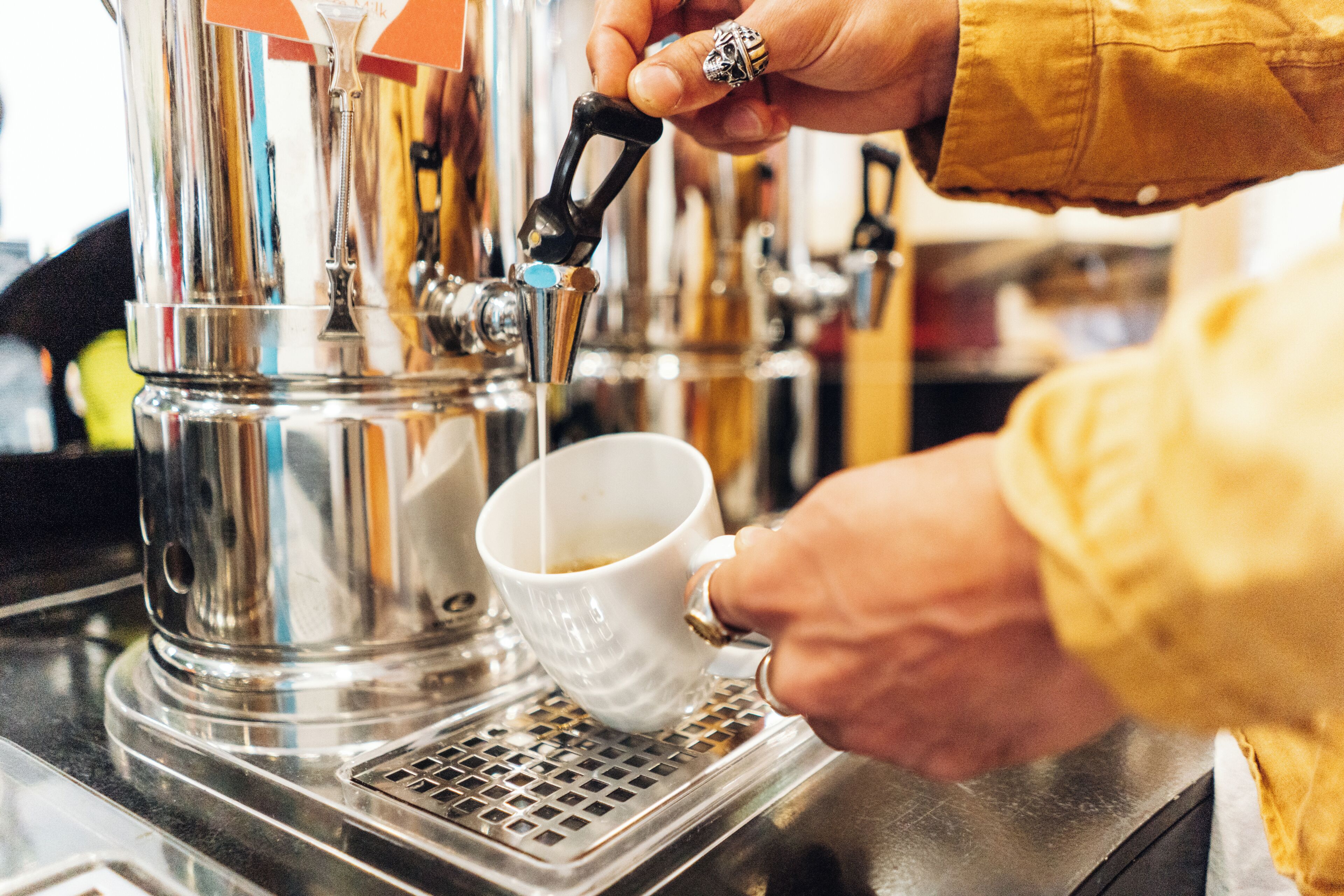 Alguém a preparar café numa máquina, com uma chávena no suporte.
