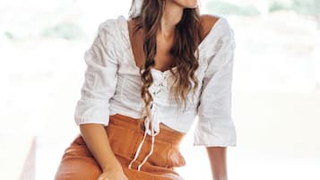 Una persona sentada en una habitación con una ventana, una silla y una mesa.