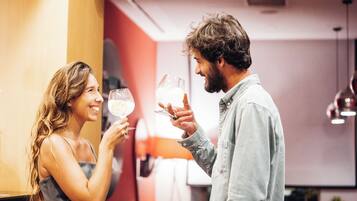Una pareja brindando con copas de vino en un interior moderno con paredes rojas y blancas.