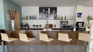 Zona de bar con una barra larga, varias sillas y una variedad de botellas.