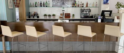 Uma área de bar com um balcão comprido, várias cadeiras e uma variedade de garrafas.
