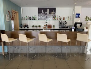 Zona de bar con una barra larga, varias sillas y una variedad de botellas.