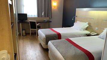 Habitación de hotel con dos camas, un escritorio, una silla, una computadora y un teléfono.